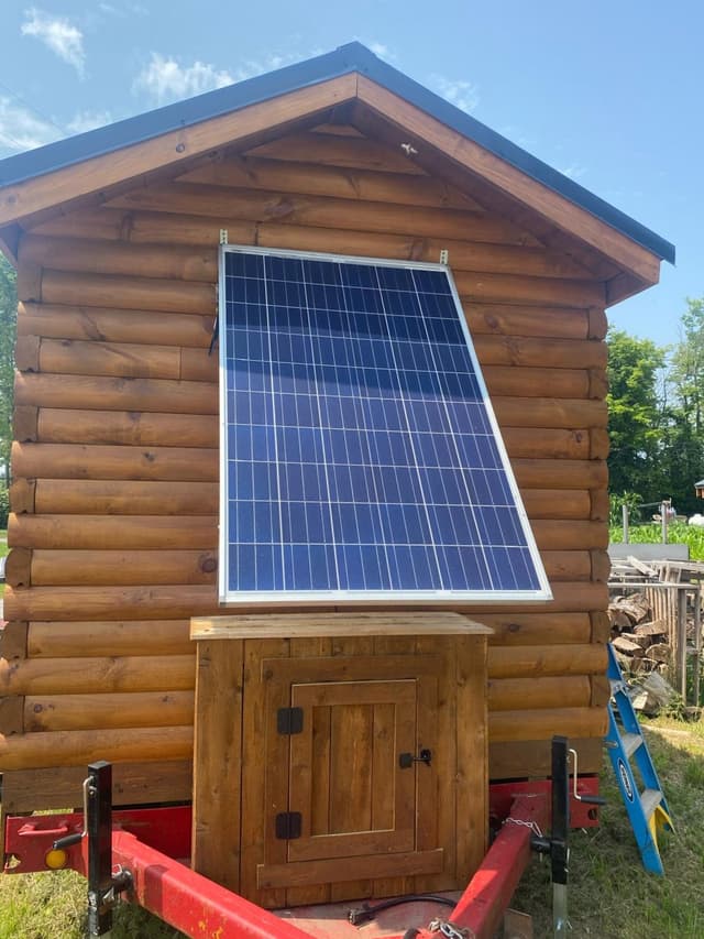 Picture of a a tiny home on a trailer with a solar panel on the back