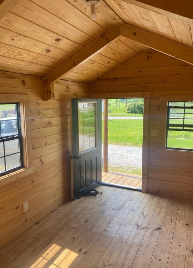 Picture of an inside of a tiny log home that has a door and windows 